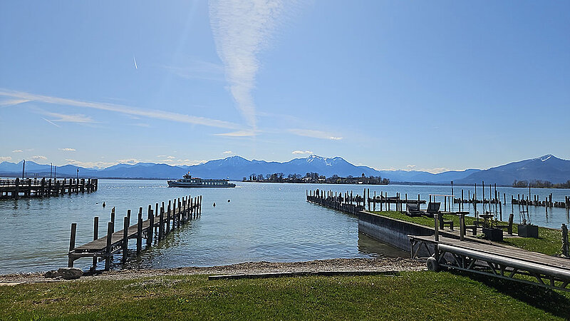 Uferpromenade und Bootsanleger in Gstadt am Chiemsee mit Blick auf die Alpen.