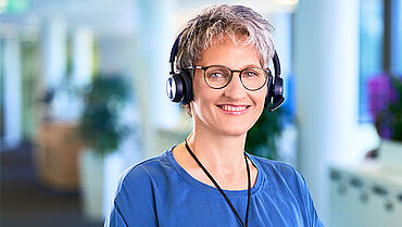 compass-Beraterin mit Headset blickt freundlich in die Kamera.