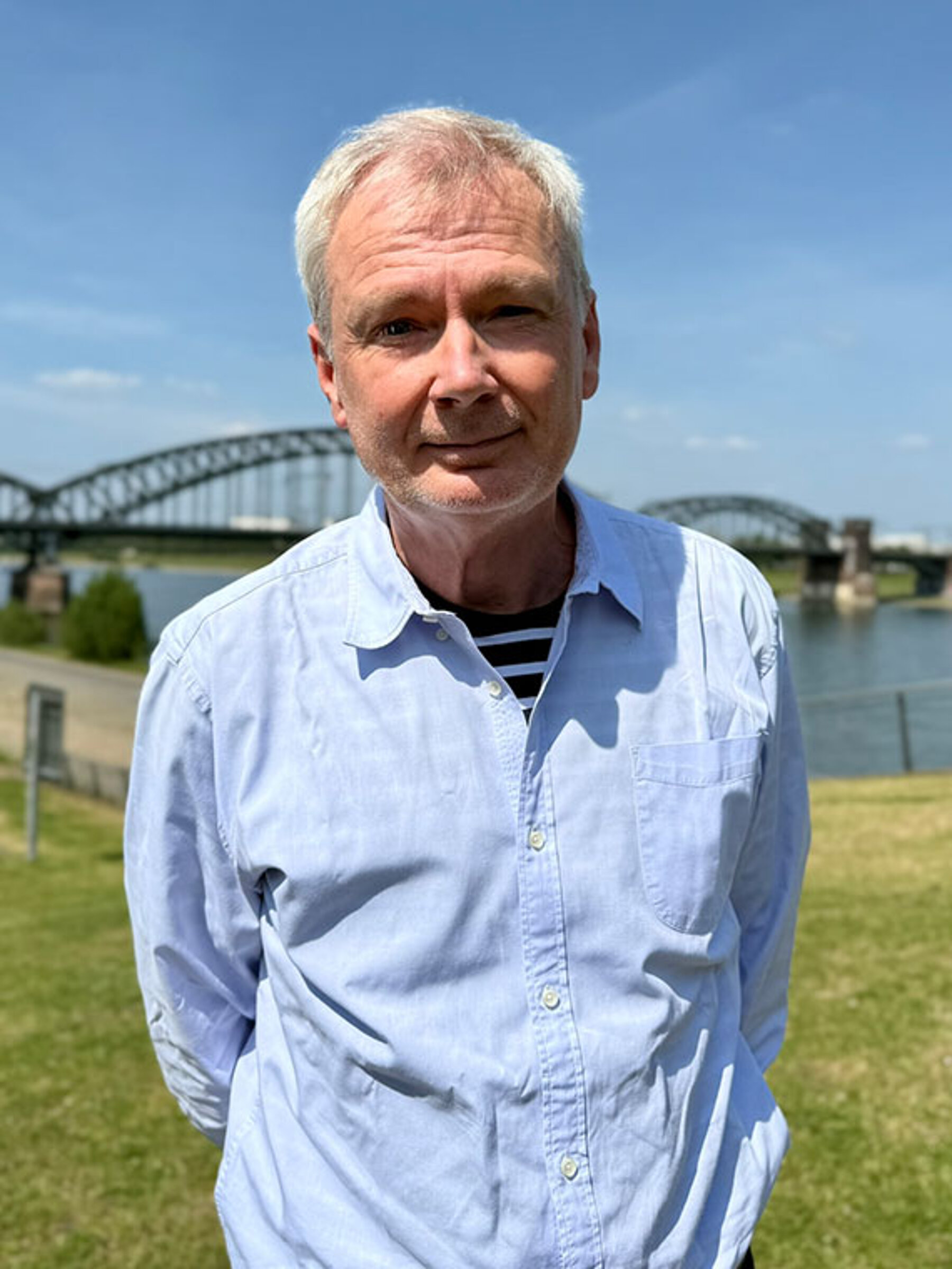 Pflegeberater Olaf Arps am Rhein in Köln. Im Hintergrund die Südbrücke.