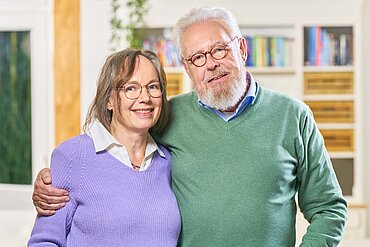 Zwei ältere Menschen lachen in die Kamera. Der Mann hat den Arm um die Frau gelegt.