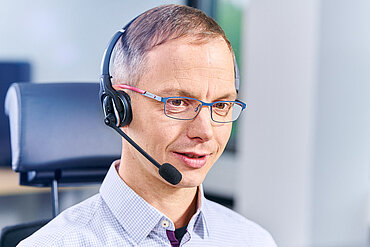 compass-Pflegeberater auf einem Bürostuhl spricht in ein Headset.