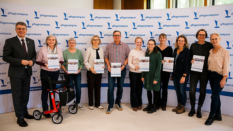 Eine Gruppe Personen steht in einer Reihe und hält Urkunden vom Pflegepreis in der Hand. Der Landrat steht neben den nominierten Personen.