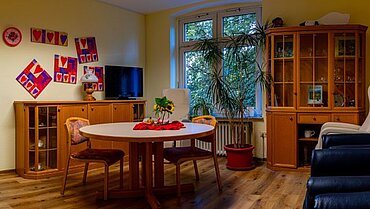 Eindruck aus der Tagespflege: Ein gemütlicher Aufenthaltsraum mit Holzmöbeln und Wanddekoration.