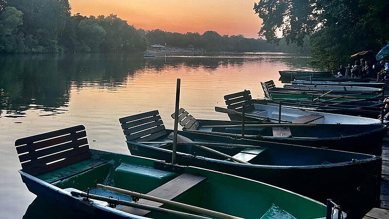 Sonnenaufgang am See mit Paddelbooten im Vordergrund. 