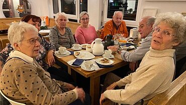 Gäste beim Café Vergissmeinnicht sitzen zusammen an einem Tisch.