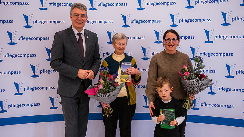 Der Landrat, zwei Frauen und ein kleiner Junge stehen in einer Reihe. Die beiden Frauen halten Blumensträuße in den Händen.