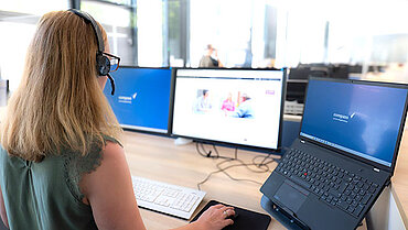compass-Beraterin mit Headset blickt freundlich in die Kamera.