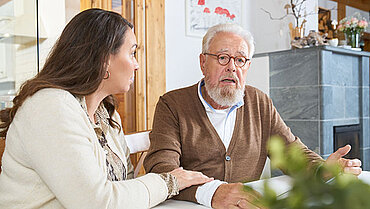 Eine junge Frau spricht mit einem besorgten älteren Mann