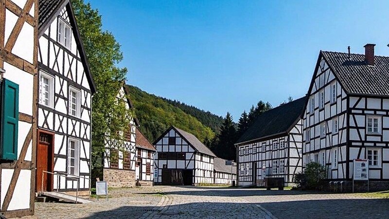 Im Vordergrund ist eine gepflasterte Straße, rechts und links stehen altertümliche Fachwerkhäuser. 