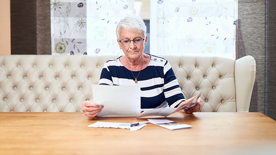 Seniorin sieht Dokumente durch