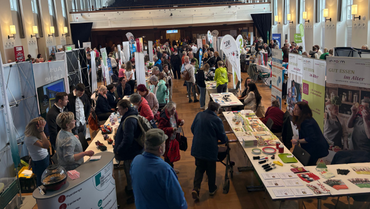 Eine Messehalle mit vielen Besucher*innen, die herumlaufen oder an Ständen stehen und schauen.