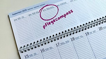 Auf dem Bild ist ein Tischkalender zu sehen. Der 17. September ist eingekreist. Daneben steht "pflegecompass".