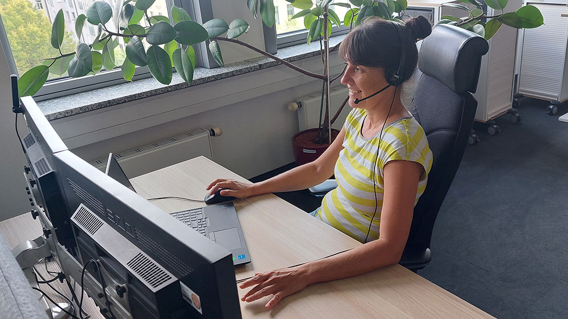Eine Disponentin trägt ein Headset und sitzt an ihrem Schreibtisch.