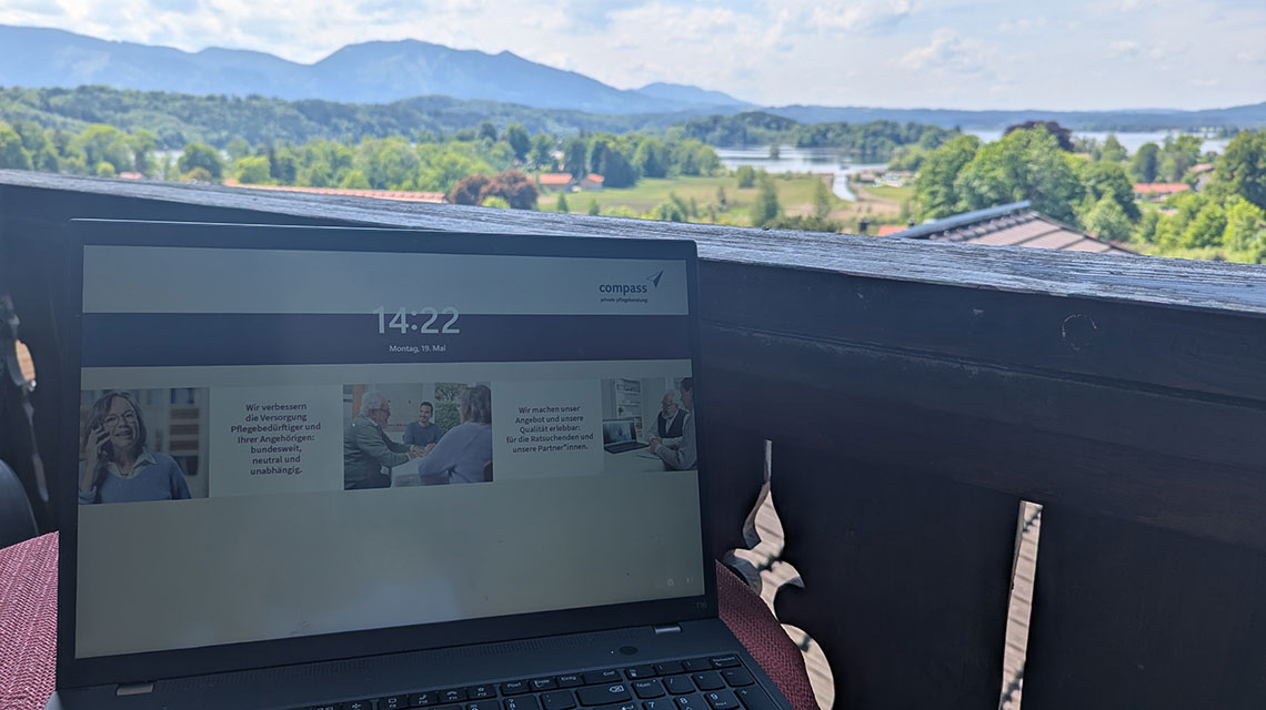 Auf dem Bild sieht man ein Laptop mit einem Bildschirmschoner von compass und im Hintergrund den Staffelsee sowie die Berge. 