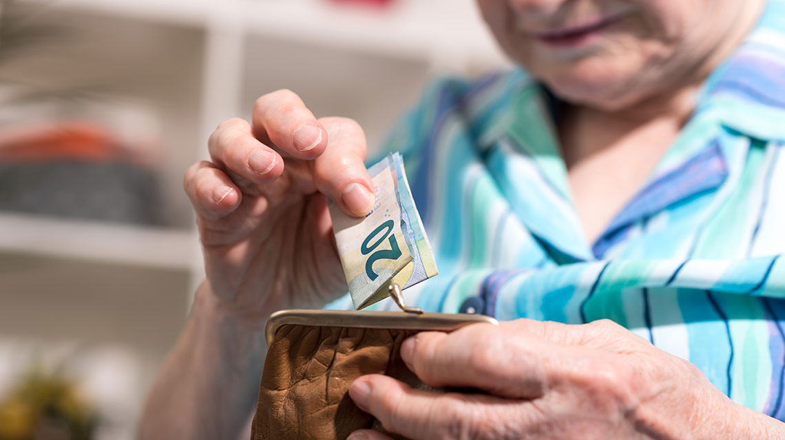 Eine Frau mit einer Geldbörse und einem Gelschein in den Händen