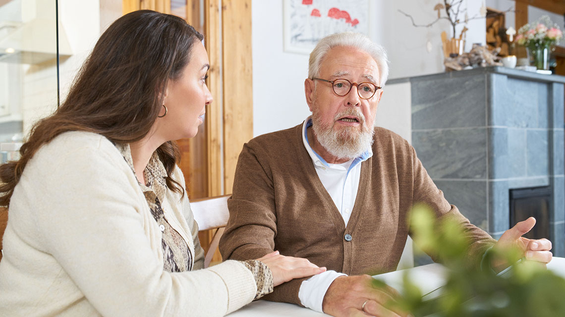 Eine junge Frau spricht mit einem besorgten älteren Mann